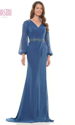A woman smiles against a plain white background, modeling the Marsoni MV1273—an elegant, floor-length long sleeve formal dress featuring floral embroidery at the waist.