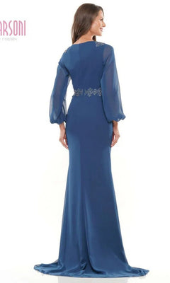 A woman is seen from the back in the Marsoni MV1273 Long Formal Dress, a blue evening gown with sheer long sleeves and decorative waist detail, set against a plain white background.
