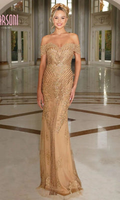 A woman poses indoors on a polished marble floor wearing the Marsoni MV1275 long formal dress in gold, featuring an off-the-shoulder neckline and beaded embellishments.