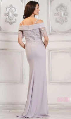 A woman stands in an ornate, light-colored room wearing the Marsoni MV1295 Long Formal Dress, a floor-length lavender gown with off-the-shoulder lace details and sequin-embroidered appliques.