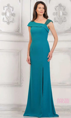 A woman in a teal green Marsoni MV1296 long formal dress with an off-the-shoulder neckline and front slit stands against an ornate white wall.
