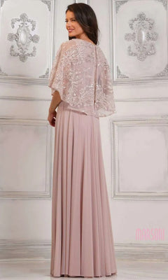 A woman poses in the Marsoni MV1302 long formal dress, featuring beaded details and a sheer embellished capelet, in an ornate, light-colored room.