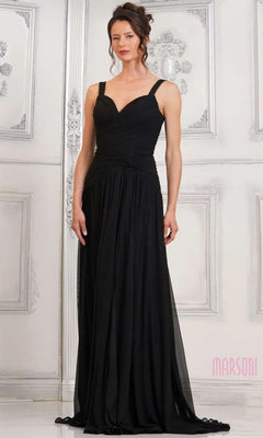 A woman in a black Marsoni MV1316 long formal dress with a ruched bodice stands indoors against an ornate white wall.