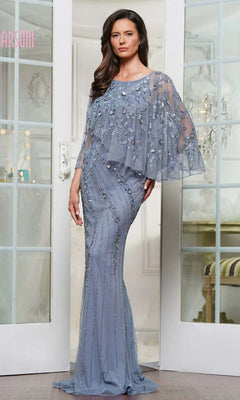A woman stands indoors wearing the Marsoni MV1343, a modest slate blue long formal dress featuring bead and sequin embellishments and a sheer cape detail.