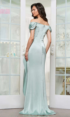 A woman stands indoors facing away from glass-paneled doors, wearing the Marsoni MV1351 Long Formal Dress—an off-the-shoulder, light blue evening gown with a fitted silhouette and slight train.