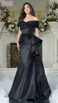 A woman in the Long Formal Dress: Marsoni MV1354 in black stands before a decorated fireplace adorned with floral and ornament arrangements.