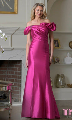 A woman stands indoors wearing the Marsoni MV1407 long formal dress in fuchsia, featuring ruffles, an off-shoulder design, floor-length satin fabric, and a decorative shoulder detail.