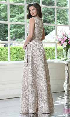 A woman wears a sleeveless, metallic leaf-patterned Marsoni MV1421 A-line formal dress with a high embellished neckline while standing in front of a window.