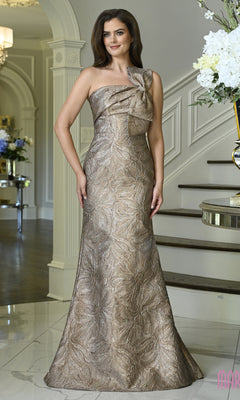 A woman wearing the taupe Marsoni MV1429 long formal dress, featuring a one-shoulder design, floral jacquard texture, and a structural bow detail on the bodice.
