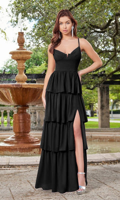 A woman wearing the Velvi Ruffled Long V-Neck Maxi Party Dress Miriam, featuring a thigh-high slit, stands outdoors near a fountain with silver high heels and long earrings.
