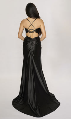 A woman wearing the Long Prom Dress: Nina Canacci 4435—a black satin gown with crisscross straps, open back, and wrap-style leg slit—stands against a plain light background, facing away from the camera.