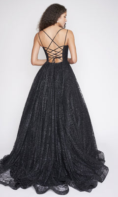 A woman models the Nina Canacci 8220 long black glitter tulle prom dress with a lace-up open back and thin crisscross straps, standing against a plain white background.