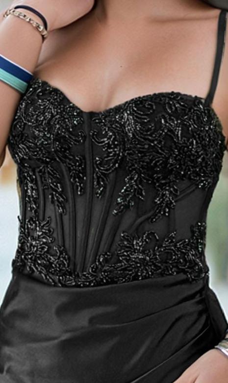 A person wearing the PromGirl PD124S, a short black corset homecoming dress with thin straps and beaded details, holds their arm near their chest.
