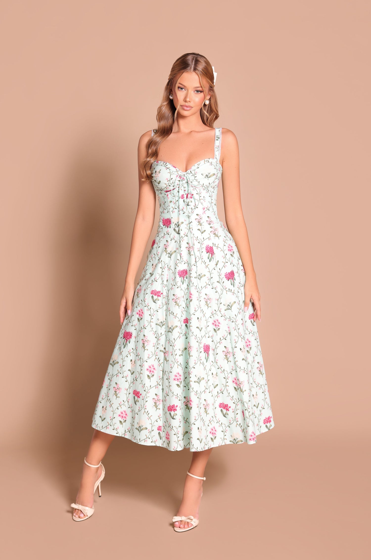 A woman stands against a beige background wearing the Mint Green Floral Casual Midi Dress: Celenia with strappy heels.