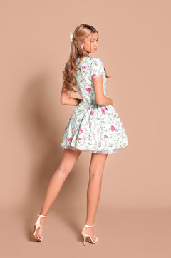 A woman poses with her back partially turned, wearing the Mint Green Short Casual Dress: Analise and high heels against a plain beige background.