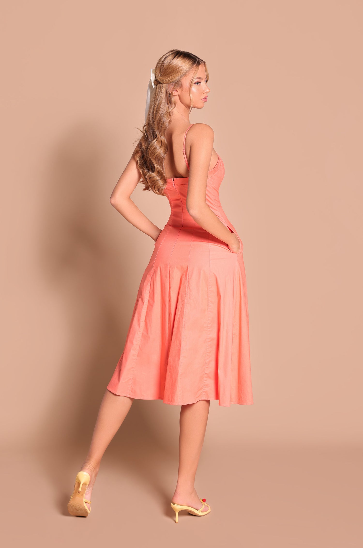Woman with long blonde hair in yellow heels poses with one hand on her hip, wearing the Papaya Midi Casual Summer Dress: Auberine against a beige background.