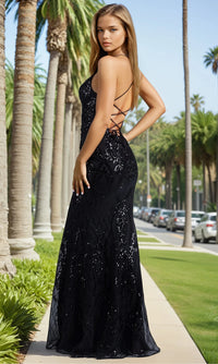 Woman in a black sequin dress standing on a palm tree-lined street.