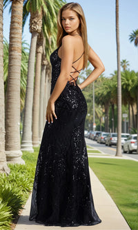 Woman in a black sequin dress standing on a palm tree-lined street.