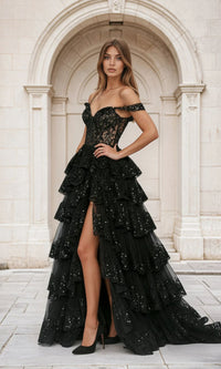 Woman wearing a black a-line tiered dress with ruffled layers in front of a classical building.