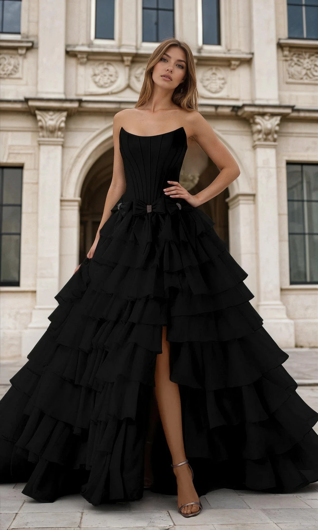 Woman wearing a black tiered dress in front of an architectural building.