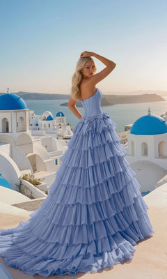 Woman in a blue gown standing in front of iconic Greek architecture with blue domes.