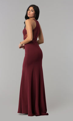 A woman stands against a plain gray background, looking over her shoulder while wearing the Illusion-Cut-Out High-Neck Long Prom Dress 8054—a sleeveless, floor-length burgundy bodycon gown.