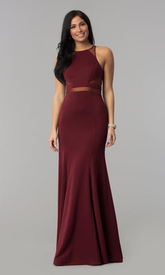 A woman wears the Illusion-Cut-Out High-Neck Long Prom Dress 8054 in burgundy, featuring a sheer waist panel and floor-length silhouette, standing against a plain gray background.