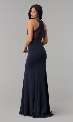 A woman models the Illusion-Cut-Out High-Neck Long Prom Dress 8054 in navy blue, featuring a sleeveless design and sheer back panel, as she looks over her shoulder against a plain gray background.
