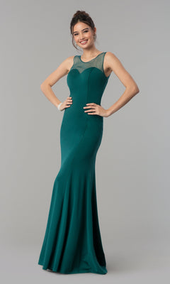 A woman smiles with her hands on her hips, wearing the green Illusion-Neckline Long Jersey Formal Prom Dress 8148, a sleeveless, floor-length gown, standing against a plain gray background.