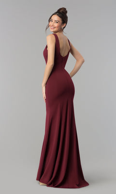 Woman models the Simple V-Neck Long Formal Jersey Prom Dress 8152 in burgundy, featuring a sleeveless v-neck design, as she smiles over her shoulder against a plain grey background.