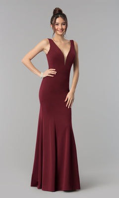 A woman in the Simple V-Neck Long Formal Jersey Prom Dress 8152 in burgundy, featuring a sleeveless floor-length design with a deep v-neckline, stands against a plain gray background.