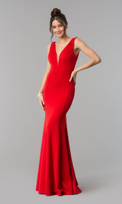 A woman wears the Simple V-Neck Long Formal Jersey Prom Dress 8152, a sleeveless, floor-length red gown with a deep V-neckline, standing against a plain gray background.