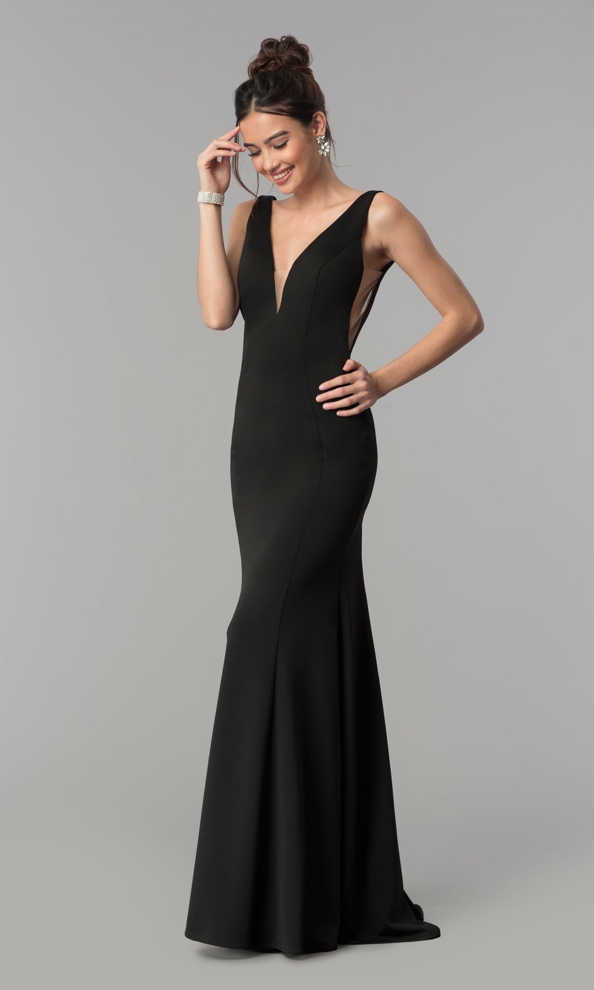 A woman poses against a plain gray background in the sleeveless V-Neck Long Formal Prom Dress 8158 in black, with one hand on her hip and the other touching her hair.