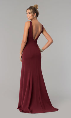 A woman models the Sleeveless V-Neck Long Formal Prom Dress 8158 in burgundy, featuring a floor-length skirt and deep V-back, as she gazes over her shoulder against a plain gray backdrop.