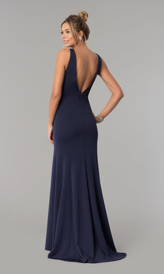 A woman models the Sleeveless V-Neck Long Formal Prom Dress 8158 in navy blue, featuring a deep V-back, as she stands facing away against a plain gray background.