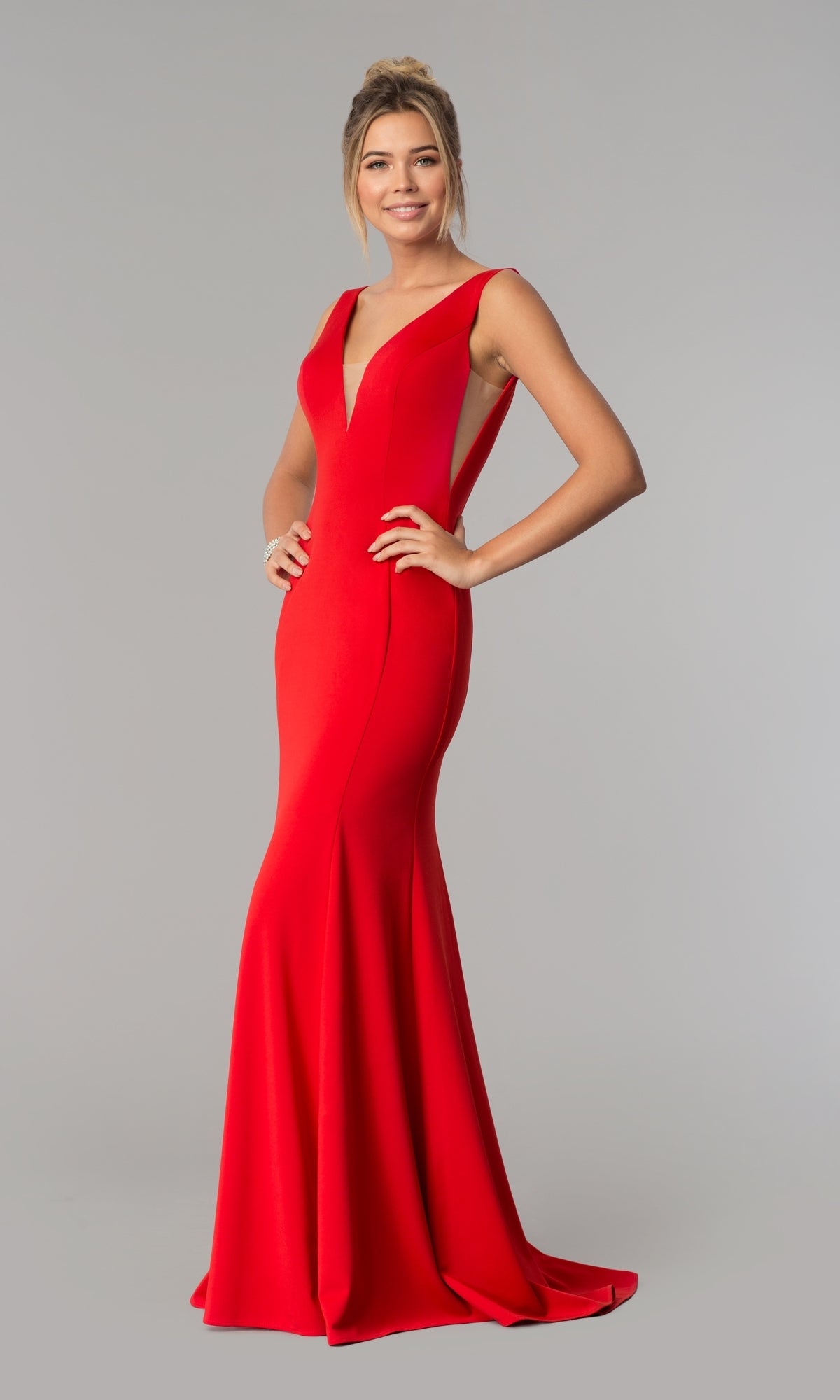 A woman stands smiling against a plain gray background, wearing the Sleeveless V-Neck Long Formal Prom Dress 8158 in deep red—a floor-length gown with a flattering silhouette.