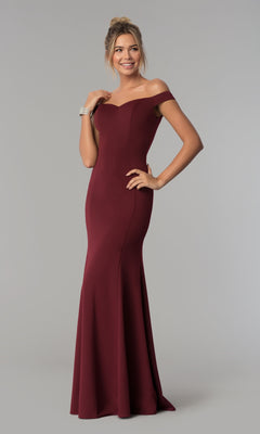A woman in the Simple Off-the-Shoulder Long Formal Prom Dress 8160, burgundy, stands against a plain light gray background, smiling with one hand on her hip.