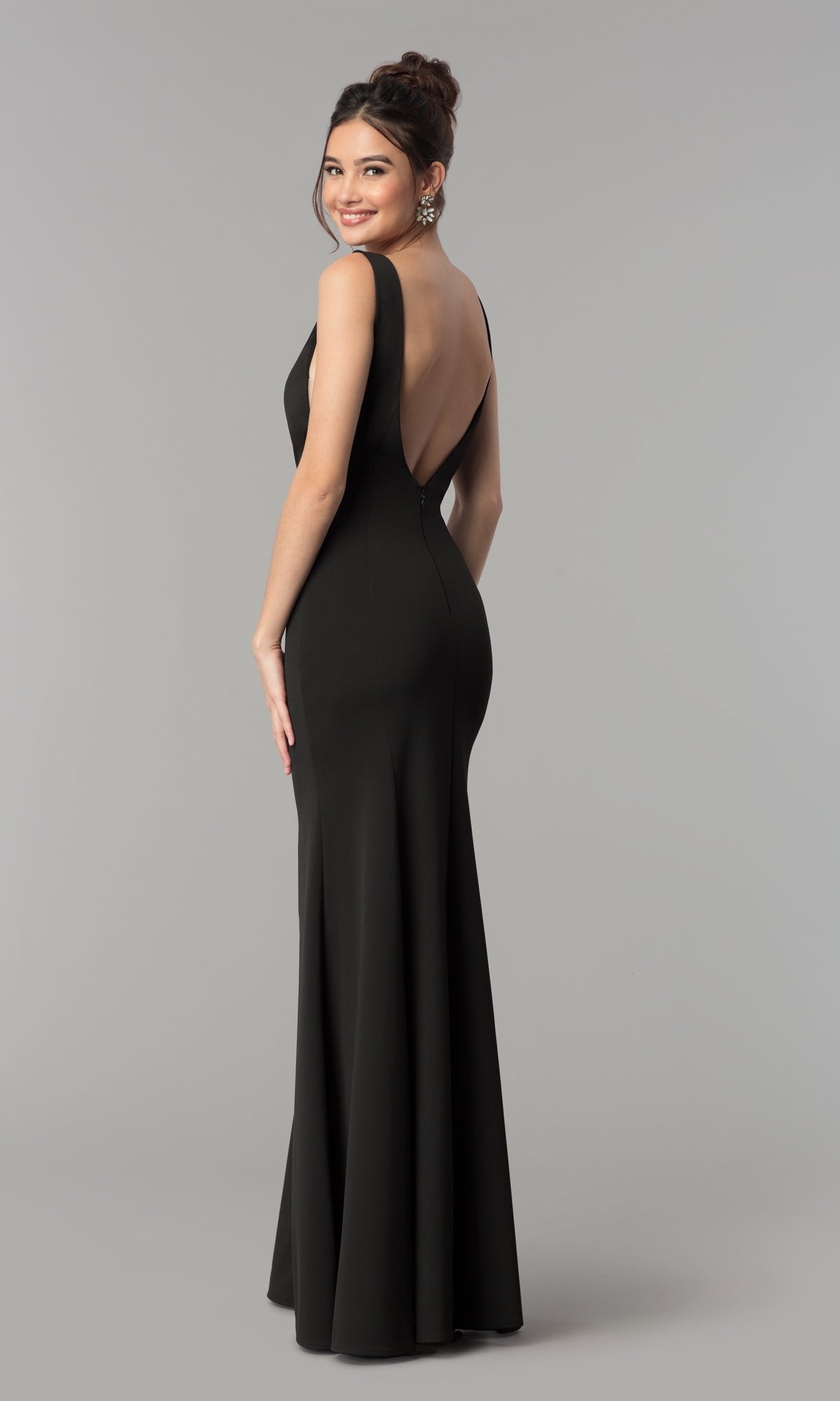 A woman stands sideways and smiles against a plain gray background, modeling the Sheer-Sided Backless Long Formal Prom Dress 8168.