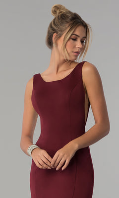 A woman models the Sheer-Sided Backless Long Formal Prom Dress 8168—sleeveless, fitted, burgundy jersey with a boat neckline—paired with a pearl bracelet and loose bun hairstyle against a plain gray background.