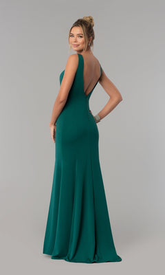 A woman models the Sheer-Sided Backless Long Formal Prom Dress 8168, an emerald green, floor-length gown with a deep V-back, as she stands looking over her shoulder against a plain background.