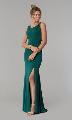 A woman models the Sheer-Sided Backless Long Formal Prom Dress 8168 in green—sleeveless, floor-length with a thigh-high slit—paired with nude heels and bracelets, against a plain gray background.
