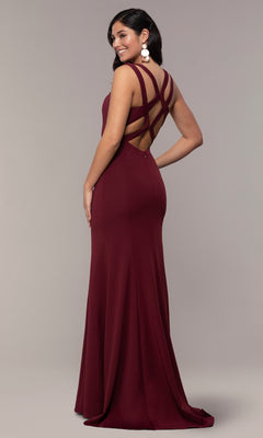 Smiling woman stands sideways in the Strappy-Open-Back Long Formal Prom Dress 8232—a floor-length, sleeveless burgundy gown with crisscross straps and an elegant open back.