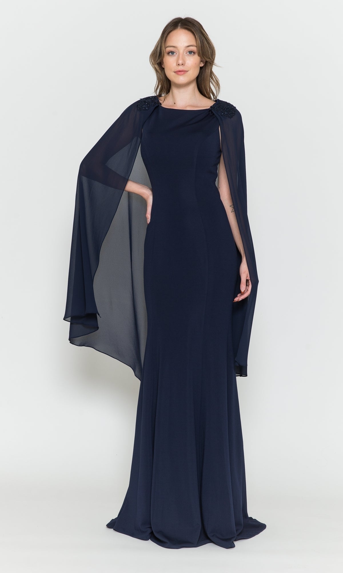 A woman stands against a plain white background wearing the High-Neck Simple Long Jersey Prom Dress 8566—a navy blue, floor-length gown with sheer, cape-like sleeves.