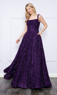 A woman stands indoors wearing the Velvet-Sequin Long A-Line Prom Gown (Poly USA 9106), a floor-length, sleeveless sequin dress with a square neckline, smiling as she holds one side of the skirt.