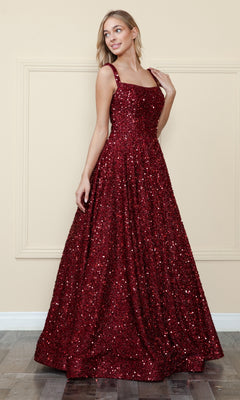 A woman stands indoors against a beige wall, wearing the Poly USA 9106 Velvet-Sequin Long A-Line Prom Gown—a floor-length, sleeveless red dress with a square neckline.