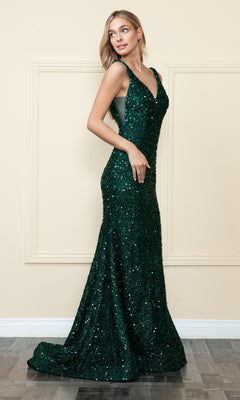 A woman stands sideways against a beige wall with decorative molding, wearing the V-Neck Long Sequin Prom Dress 9108, a sleeveless, floor-length, dark green gown.