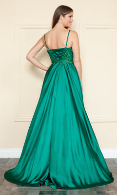 A woman stands facing away in a simple indoor setting, wearing the Sheer-Corset Long Satin Prom Dress Poly USA 9126—an emerald green, a-line gown featuring thin straps and a lace-up back.