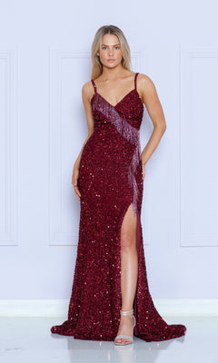 A woman models the Beaded-Fringe Long Sequin Prom Dress 9154 in deep red, featuring a sleeveless design, thigh-high slit, and sparkling beaded fringe detail, standing by a light-colored wall.