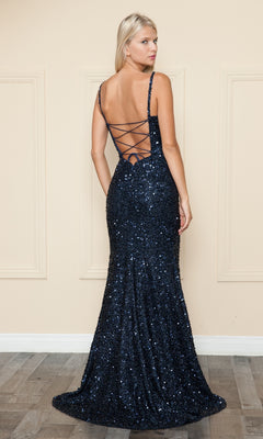 A woman stands with her back to the camera in the Beaded-Fringe Long Sequin Prom Dress 9154, a dark blue gown featuring a lace-up open back, against a neutral wall.