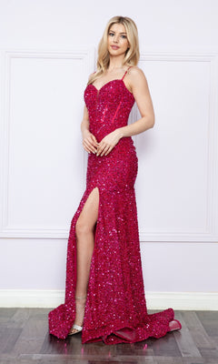 A woman stands before a white wall in the Long Sequin Prom Dress with Lace-Up Back 9172, featuring a sparkling hot pink design, corset bodice, spaghetti straps, and a thigh-high slit.